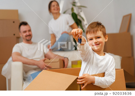 Portrait of happy family with cardboard boxes in new house at moving day Portrait of happy family with cardboard boxes in new house at moving day 92033636