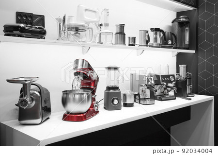 Household appliances for the kitchen. Sale of electrical equipment for cooking at home. Coffee makers, mixers, meat grinders, blenders, coffee machines, toasters and kettles on a shelf in the interior Household appliances for the kitchen. Sale of electrical equipment for cooking at home. Coffee makers, mixers, meat grinders, blenders, coffee machines, toasters and kettles on a shelf in the interior 92034004