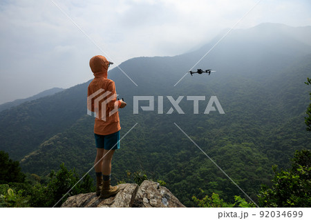 Woman remotel control a flying drone in spring forest 92034699