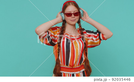 Cheerful redhead girl listening music via headphones and dancing disco fooling around having fun 92035446