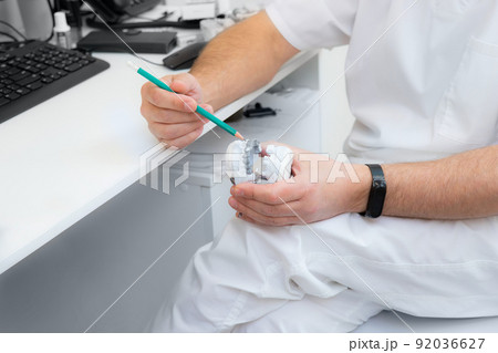 hands of a dentist close-up. dentist with a pencil shows jaw defects on a plaster cast. hands of a dentist close-up. dentist with a pencil shows jaw defects on a plaster cast. 92036627
