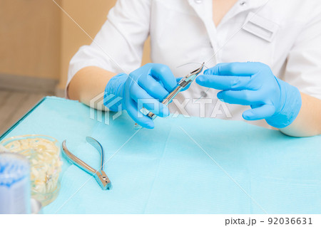 Orthodontic treatment. Alignment of the dentition or bite. Unrecognizable person. Hands in protective gloves close-up with a tool. Orthodontic treatment. Alignment of the dentition or bite. Unrecognizable person. Hands in protective gloves close-up with a tool. 92036631