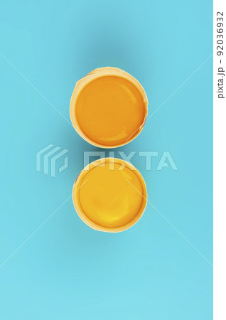 Two raw chicken egg yolks in broken shells vertical on blue background 92036932