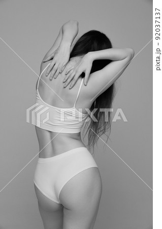 Portrait of young girl with slim tender figure posing in white underwear. Black and white photography aesthetics 92037137