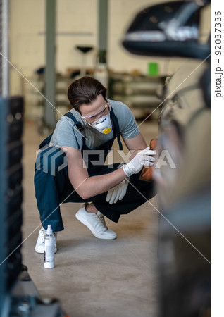 Professional mechanic in the respirator buffing the customer car Professional mechanic in the respirator buffing the customer car 92037336