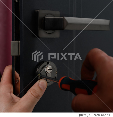 Installation of a door lock, a carpenter installs a door lock in a door, work close-up. Installation of a door lock, a carpenter installs a door lock in a door, work close-up. 92038274