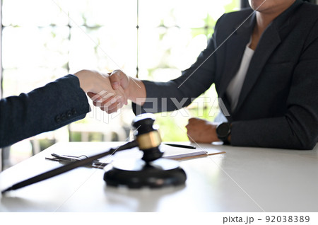Female lawyer shaking hands to greeting her client, having a formal meeting Female lawyer shaking hands to greeting her client, having a formal meeting 92038389