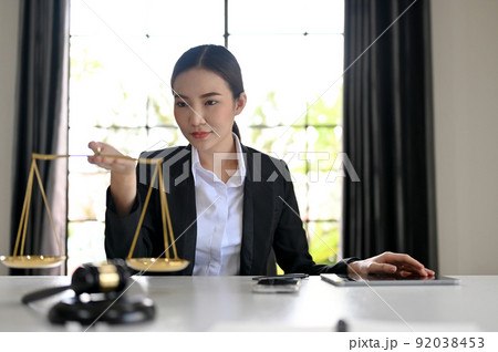 Beautiful Asian female lawyer or law consultant hold a scales of justice 92038453