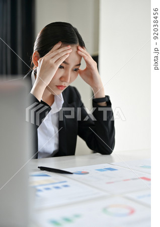 Stressed and serious Asian businesswoman or financial consultant reading a financial report Stressed and serious Asian businesswoman or financial consultant reading a financial report 92038456