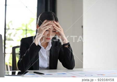 Young Asian businesswoman thoughtful and serious, pensively thinking about her financial plan Young Asian businesswoman thoughtful and serious, pensively thinking about her financial plan 92038458