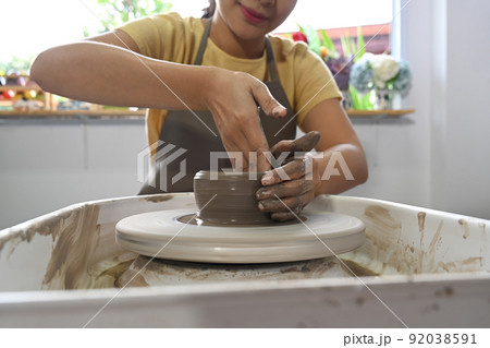 Young woman wearing apron creating handmade ceramic bowl in a pottery workshop 92038591