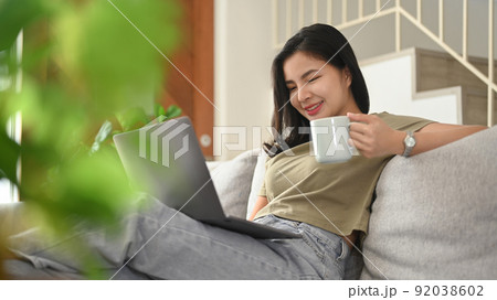 Joyful young woman browsing internet, chatting with friends on laptop computer 92038602