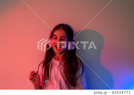 A dancing beautiful little girl in pink headphones A dancing beautiful little girl in pink headphones 92039771