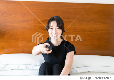 テレビをリモコンで操作する若い女性 テレビをリモコンで操作する若い女性 92044207