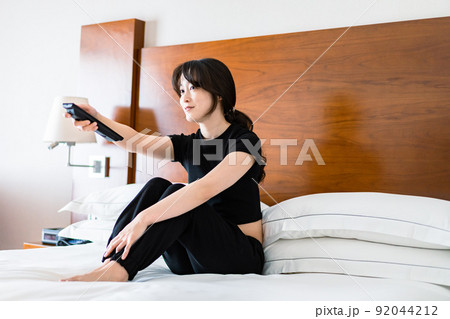 テレビをリモコンで操作する若い女性 テレビをリモコンで操作する若い女性 92044212