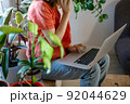 Young female using laptop at home checking email, writing message in social network, searching information. Cozy workplace, remote work learning concept. 92044629