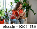 Young female using smartphone at home checking email, writing message in social network, searching information.  92044630