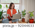 Young female using laptop at home checking email, writing message in social network, searching information. Cozy workplace, remote work learning concept. 92044633