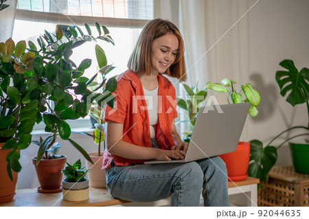 Young female using laptop at home checking email, writing message in social network, searching information. Cozy workplace, remote work learning concept. Young female using laptop at home checking email, writing message in social network, searching information. Cozy workplace, remote work learning concept. 92044635