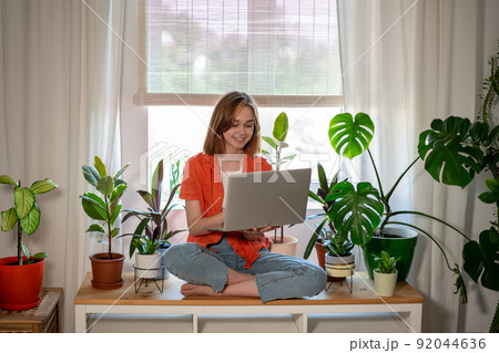 Young female using laptop at home checking email, writing message in social network, searching information. Cozy workplace, remote work learning concept. Young female using laptop at home checking email, writing message in social network, searching information. Cozy workplace, remote work learning concept. 92044636