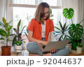 Young female using laptop at home checking email, writing message in social network, searching information. Cozy workplace, remote work learning concept. 92044637