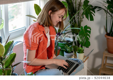 Young female using laptop at home checking email, writing message in social network, searching information. Cozy workplace, remote work learning concept. Young female using laptop at home checking email, writing message in social network, searching information. Cozy workplace, remote work learning concept. 92044638