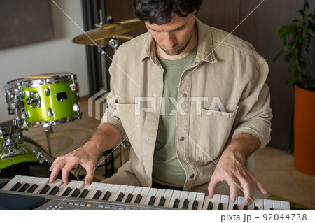 Young man plays synthesizer in equipped music studio 92044738