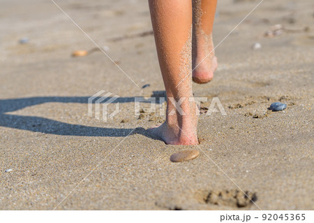 Legs of a child walking on a sandy beach. Legs of a child walking on a sandy beach. 92045365
