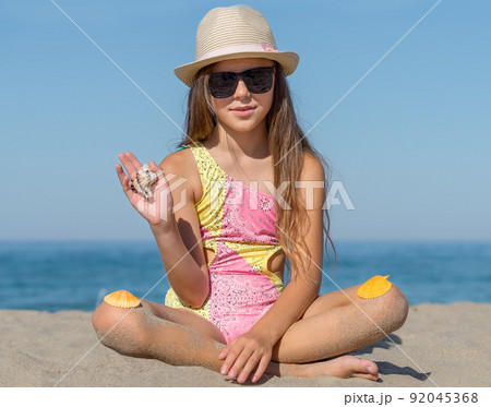 Portrait of a girl 10 years old on the beach with seashells. 92045368