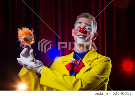 Circus clown performs number. A man in a clown outfit with a toy 92046015