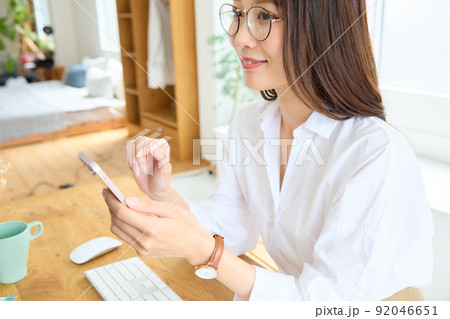 デスクでスマホを見る女性 92046651