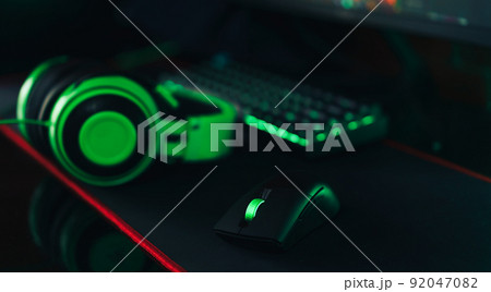 Gaming wireless accessories with green backlight next to headphones 92047082