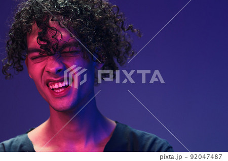 Stylish tanned curly man in black t-shirt looks at camera posing isolated on color pink blue studio background. Cool fashion offer. Virtual Reality New Collection concept. Copy space for ad 92047487