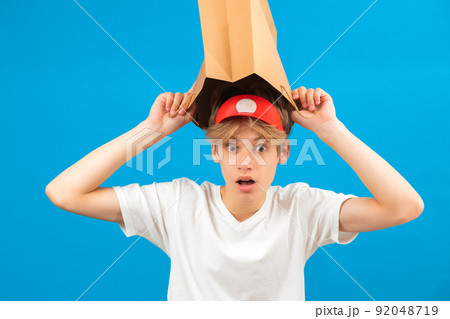 Shocked teen boy with paper bag over head. Teenager holding paper bag over the head posing in studio. Guy pulling paper bag over head. Shocked teen boy with paper bag over head. Teenager holding paper bag over the head posing in studio. Guy pulling paper bag over head. 92048719