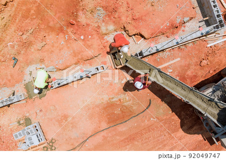 Construction workers pouring concrete columns at a building site 92049747