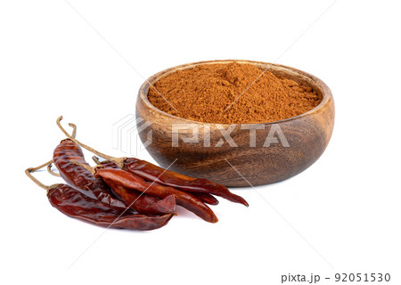 Ground red pepper in a wooden bowl and dried hot pepper pods on a white background. Ground red pepper in a wooden bowl and dried hot pepper pods on a white background. 92051530