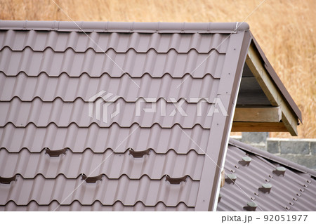 Closeup snow guard for safety in winter on house roof top covered with steel shingles. Tiled covering of building 92051977