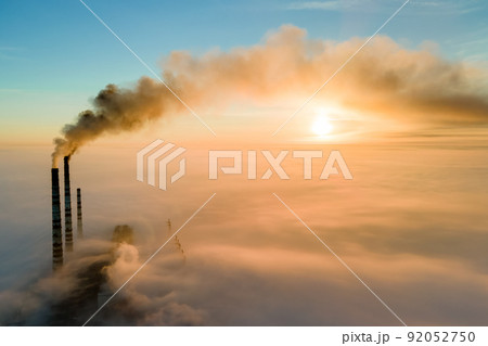 Aerial view of coal power plant high pipes with black smoke moving up polluting atmosphere at sunset. Aerial view of coal power plant high pipes with black smoke moving up polluting atmosphere at sunset. 92052750