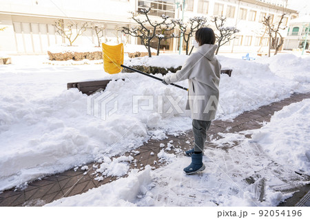 大雪の翌朝、商店街で雪かきをする女性 大雪の翌朝、商店街で雪かきをする女性 92054196