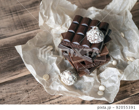 Chocolate bars tower and truffles on wooden surface. Sweet and delicious food concept Chocolate bars tower and truffles on wooden surface. Sweet and delicious food concept 92055391