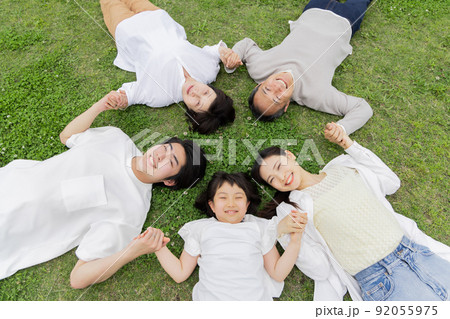 仰向けで手を繋ぎ輪を作る三世代家族 92055975