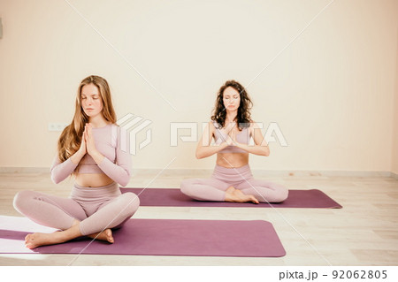 Well looking middle aged sporty woman, fitness instructor in pink sportswear doing stretching and pilates on yoga mat in the studio with mirror. Female fitness yoga. Healthy lifestyle and harmony. 92062805