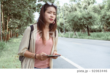Asian woman get lost and hitchhiking beside the street while traveling alone Asian woman get lost and hitchhiking beside the street while traveling alone 92063446
