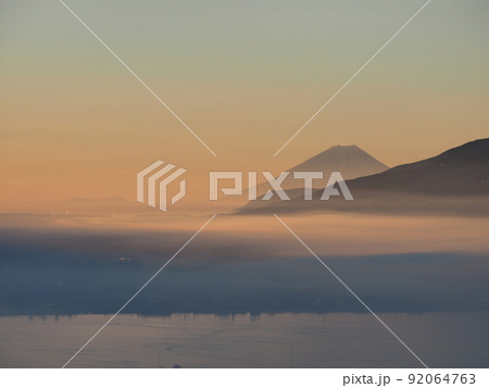 冬の塩嶺御野立公園から薄霧に煙る諏訪盆地と朝焼けの富士山を望む 92064763