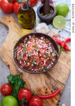freshly made salsa dip sauce - chopped garlic, tomatoes and onion in wooden bowl 92065098