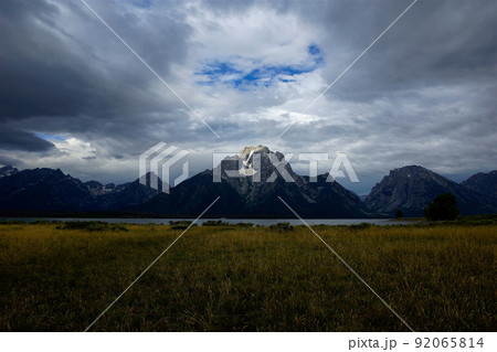 エルク島から望むグランドティートン　モラン山。雲の下残雪の岩山と湖・草原。 92065814