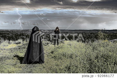 woman in a black raincoat with a hood approaches a young girl woman in a black raincoat with a hood approaches a young girl 92066177
