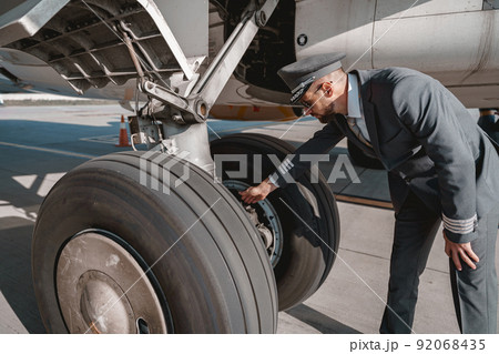 Pilot in uniform checks the aircraft before the flight in airport Pilot in uniform checks the aircraft before the flight in airport 92068435