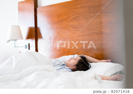 明るい時間にベッドで寝る若い女性 92071416