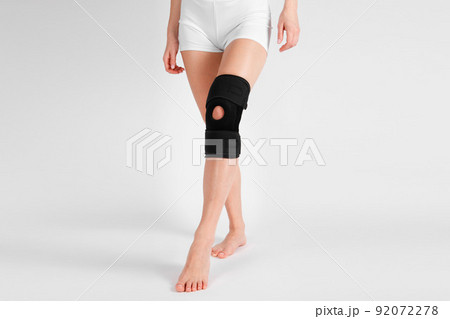 Knee Support Brace on leg isolated on white background. Elastic orthopedic orthosis. Anatomic braces for knee fixation, injuries and pain. Protective knee joint bandage sleeve. Trauma, rehabilitation. 92072278